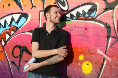 Full length of young man standing against graffiti wall