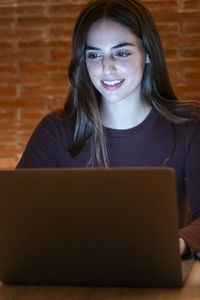 Portrait of young woman using laptop while sitting on table