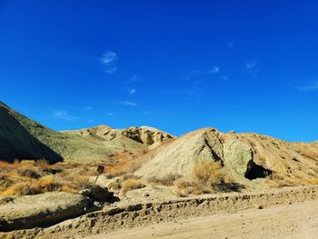 Scenic view of arid landscape against blue sky