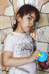 Portrait of cute girl holding face against wall