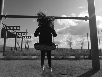 Rear view of girl standing on field against sky