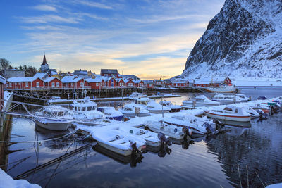 Sailboats moored in harbor against sky during winter