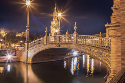 Illuminated bridge over river at night