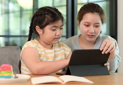 Asian girl studying privately with tutor at home, siblings teaching homework, online learning.