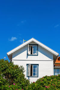 House with open windows and rose bushes in the garden