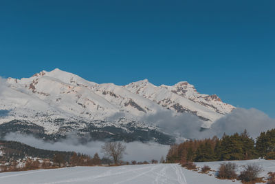 Scenic view of snowcapped mountains against clear blue sky