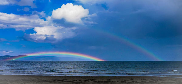 Scenic view of rainbow over sea against sky