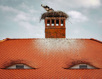 Low angle view of house on roof of building against sky