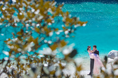 High angle view of newlywed couple romancing at beach