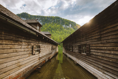 Stilt houses in lake against cloudy sky