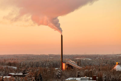 Smoke emitting from factory against sky during sunset