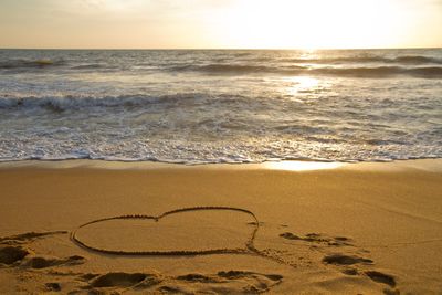 Heart shape on beach against sky during sunset