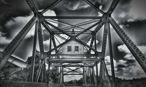 Low angle view of metal structure against cloudy sky
