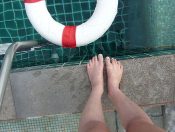 Low section of woman standing by swimming pool