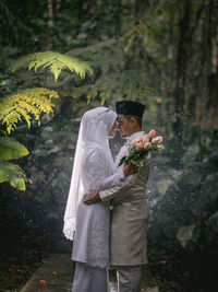 Rear view of friends standing against blurred trees