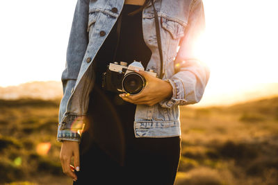 Midsection of woman photographing camera on field