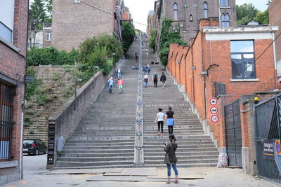 People walking on staircase amidst buildings in city