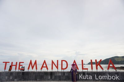 Text on wall against sky in city