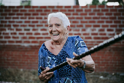 Portrait of smiling senior woman holding cane standing outdoors