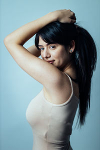 Portrait of young woman standing against colored background