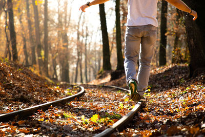 Low section of man walking on railroad track in forest