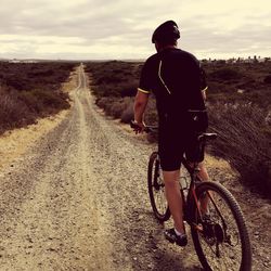 Rear view of man riding bicycle on road