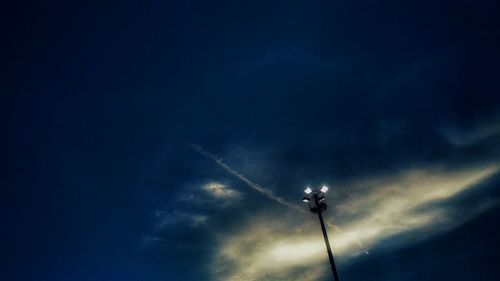 Low angle view of silhouette electricity pylon against blue sky