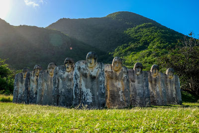 Large old statues on grass against mountains