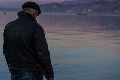 Rear view of man standing at sea shore against sky