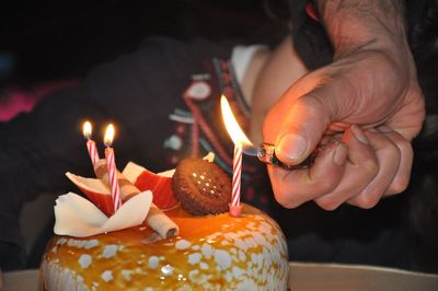 Close-up of hand holding lit candles