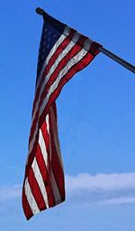 Low angle view of american flag against blue sky