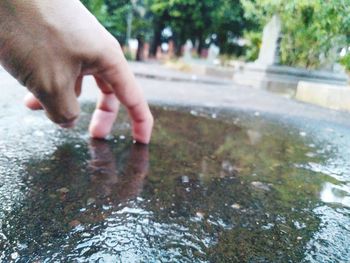 Close-up of person hand touching wet water