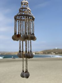 Close-up of chain hanging on beach against sky