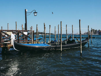 Boats moored in sea against clear blue sky