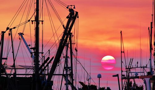 Sailboat masts against orange sky