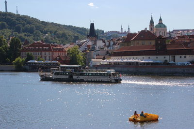 Boats in river against buildings in city