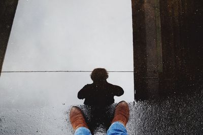 Low section of person wearing brown shoe standing next to puddle