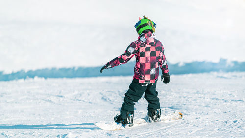 Child snowboarding in the mountains