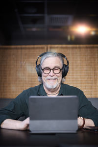 Smiling senior man with headphones using tablet