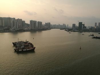 Boats in sea by buildings against sky