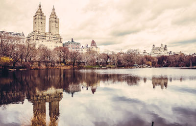 Reflection of the san remo on central park reservoir against cloudy sky