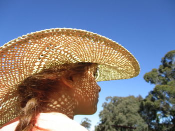 Rear view of girl wearing straw hat against clear blue sky on sunny day