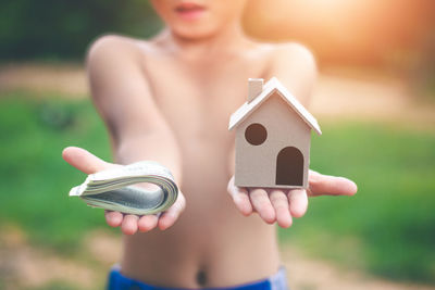 Midsection of boy holding money and model house