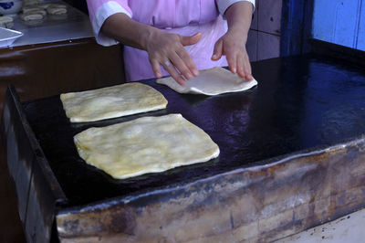 Midsection of woman cooking bread on pan