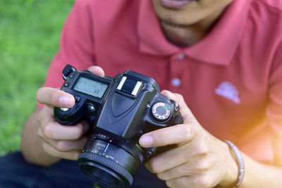 Midsection of man photographing with digital camera