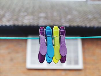 Close-up of colorful clothespins hanging from string outside house