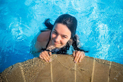 Young brunette teen girl posing in blue swimming pool in a hotel in turkey