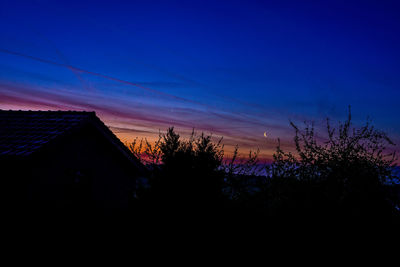 Silhouette houses against sky during sunset