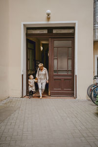 Grandmother with granddaughter walking out of building