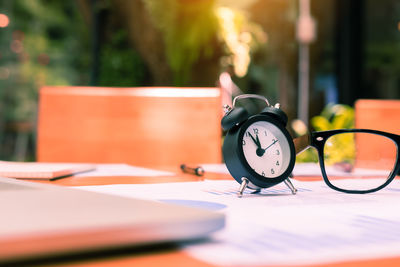 Close-up of alarm clock by eyeglasses on table